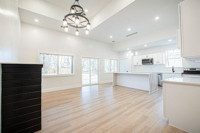 kitchen featuring stainless steel appliances, hanging light fixtures, white cabinets, and a chandelier