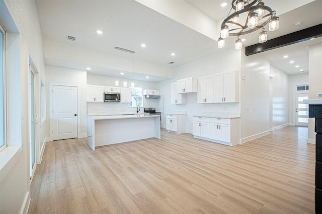 kitchen with a center island, pendant lighting, white cabinets, and light hardwood / wood-style flooring