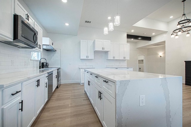 kitchen featuring pendant lighting, light hardwood / wood-style flooring, a center island, and white cabinets