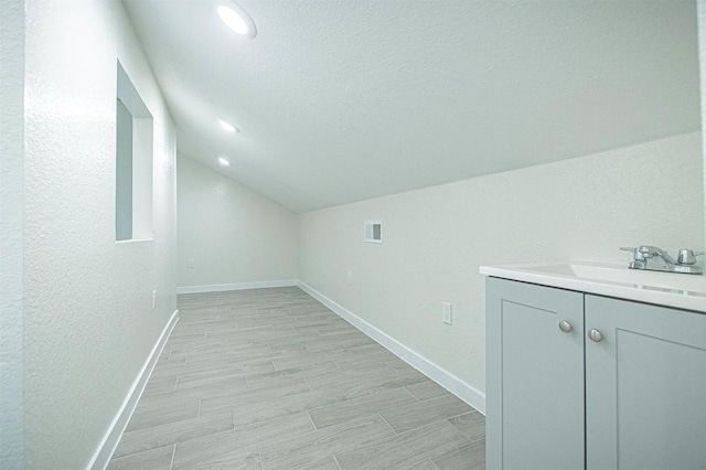 interior space featuring vaulted ceiling, sink, and a textured ceiling