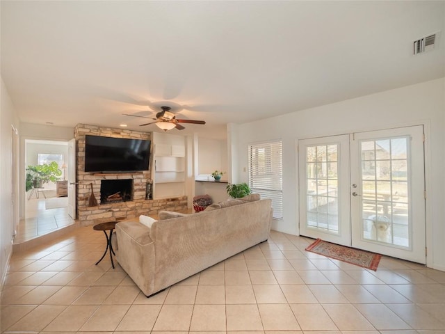 tiled living room with french doors, ceiling fan, and a fireplace