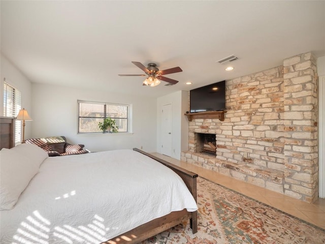 tiled bedroom featuring multiple windows, a fireplace, and ceiling fan