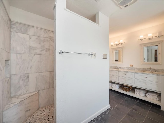 bathroom featuring tile patterned flooring, vanity, and tiled shower