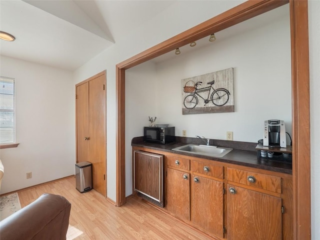 bar featuring sink and light hardwood / wood-style flooring