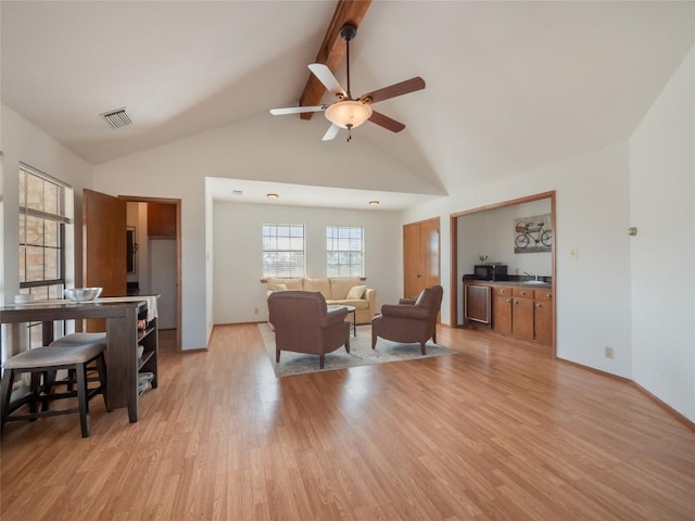 living room with beam ceiling, high vaulted ceiling, ceiling fan, and light wood-type flooring