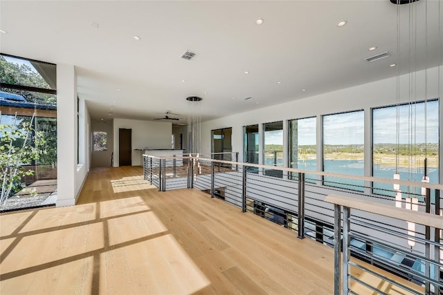 hall with a water view, a wealth of natural light, and light wood-type flooring