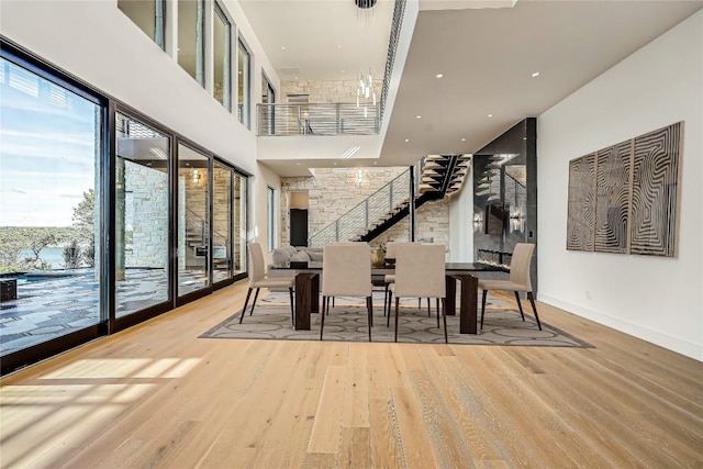 dining space featuring a towering ceiling and wood-type flooring