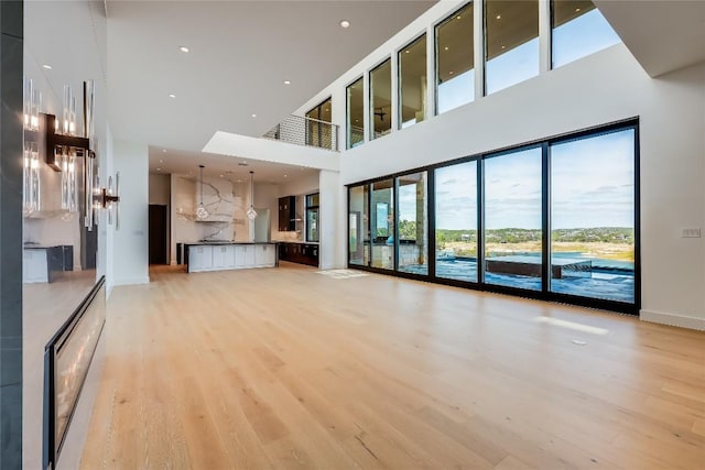 unfurnished living room with light hardwood / wood-style floors and a high ceiling