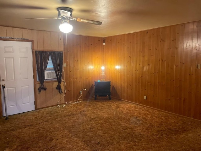 empty room with ceiling fan, wooden walls, carpet flooring, and cooling unit