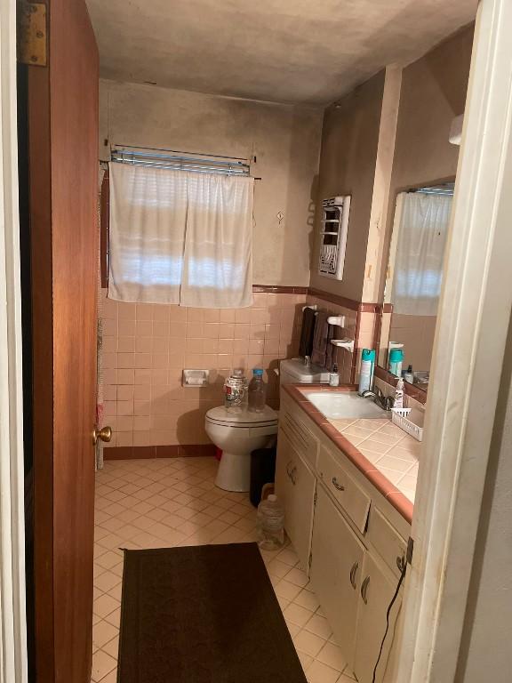 bathroom with tile patterned floors, vanity, toilet, and tile walls