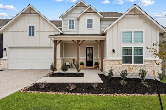 view of front of home with a porch, stone siding, driveway, roof with shingles, and board and batten siding