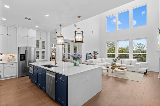 kitchen featuring visible vents, appliances with stainless steel finishes, a sink, wood finished floors, and blue cabinets