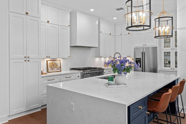 kitchen with high end appliances, white cabinetry, a spacious island, and hanging light fixtures