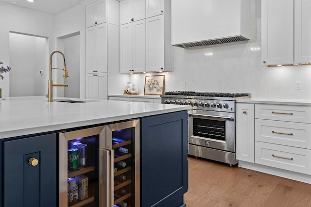 kitchen with light countertops, stainless steel stove, premium range hood, and a sink