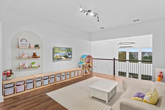 interior space featuring rail lighting, a notable chandelier, visible vents, and wood finished floors