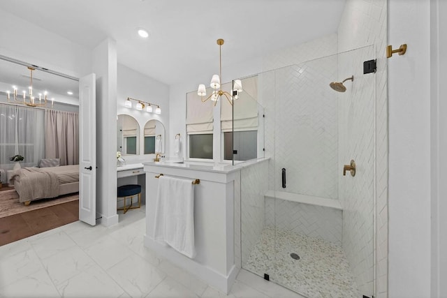 bathroom with vanity, a shower with shower door, and a notable chandelier