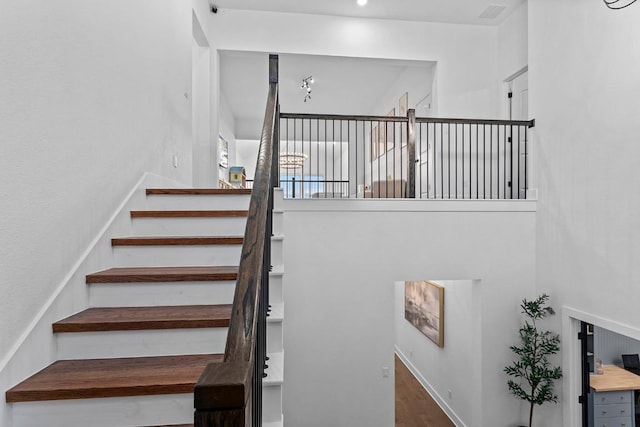 staircase featuring visible vents, a high ceiling, and wood finished floors