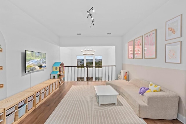 living room with wood-type flooring, rail lighting, and a chandelier