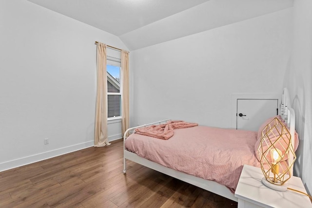 bedroom featuring lofted ceiling, baseboards, and wood finished floors