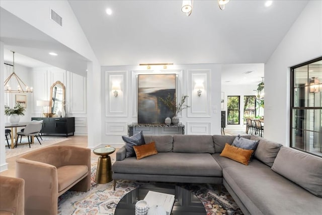 living room with lofted ceiling, a chandelier, and light wood-type flooring