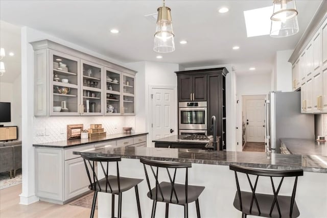 kitchen with a breakfast bar, decorative light fixtures, white cabinetry, decorative backsplash, and stainless steel appliances