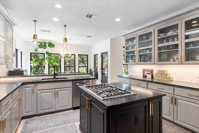 kitchen featuring sink, decorative light fixtures, appliances with stainless steel finishes, gray cabinets, and kitchen peninsula