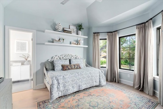 bedroom featuring vaulted ceiling, ensuite bathroom, and light wood-type flooring