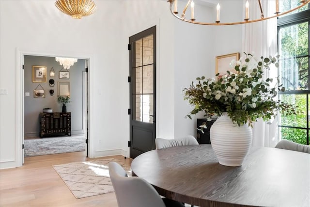 dining space with light wood-type flooring and a notable chandelier