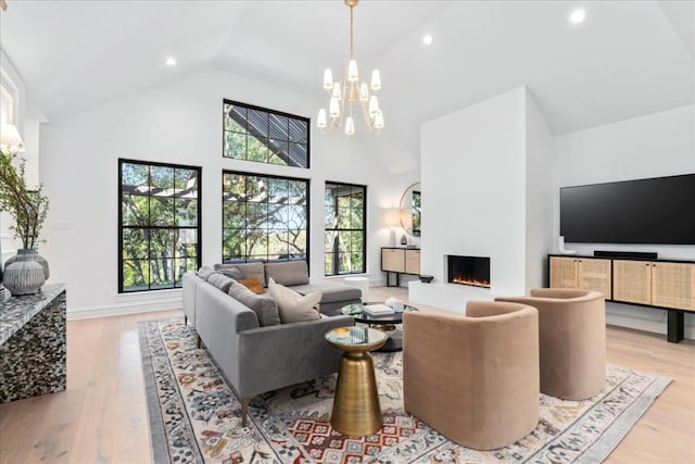 living room featuring a chandelier, light hardwood / wood-style floors, and high vaulted ceiling