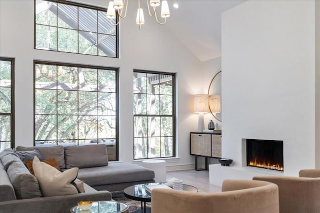 living room with high vaulted ceiling, light hardwood / wood-style floors, and a chandelier