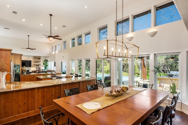 dining space with dark hardwood / wood-style floors, sink, an inviting chandelier, and a towering ceiling