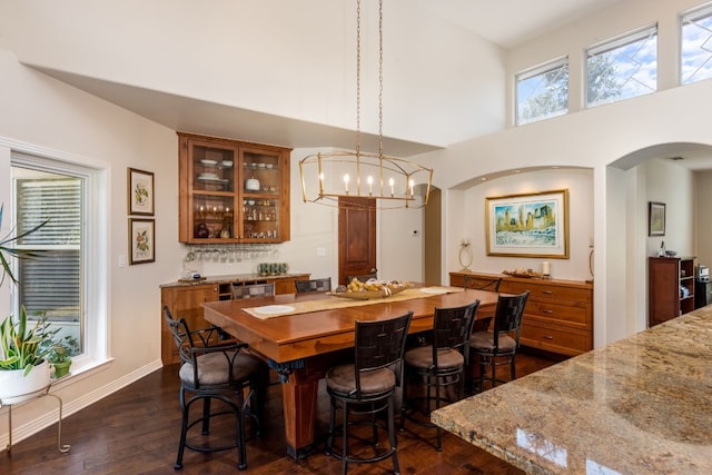 dining area featuring a towering ceiling, dark hardwood / wood-style floors, and a chandelier