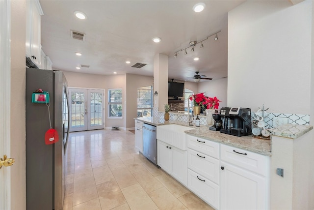 kitchen featuring stainless steel appliances, white cabinets, light stone counters, and french doors