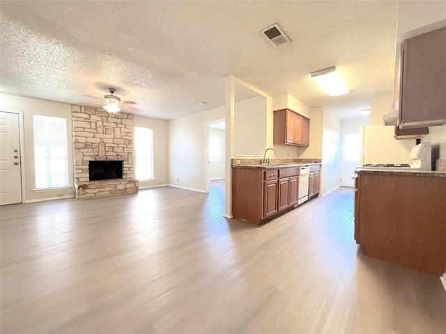 kitchen with a fireplace, sink, white dishwasher, ceiling fan, and light wood-type flooring