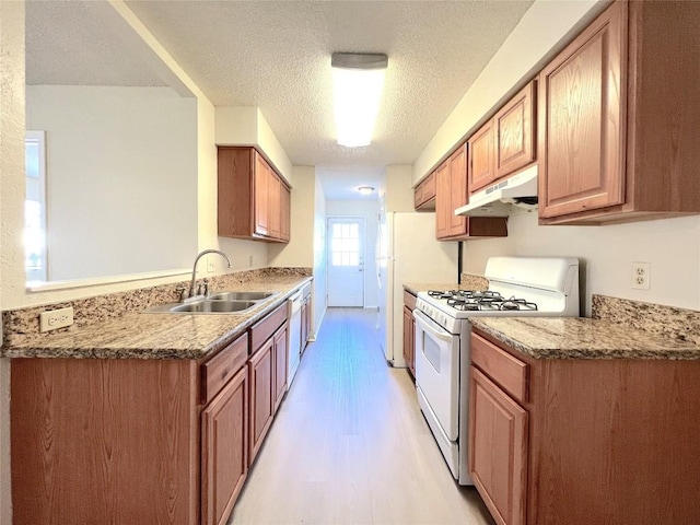 kitchen featuring sink, light stone counters, white appliances, and light hardwood / wood-style flooring