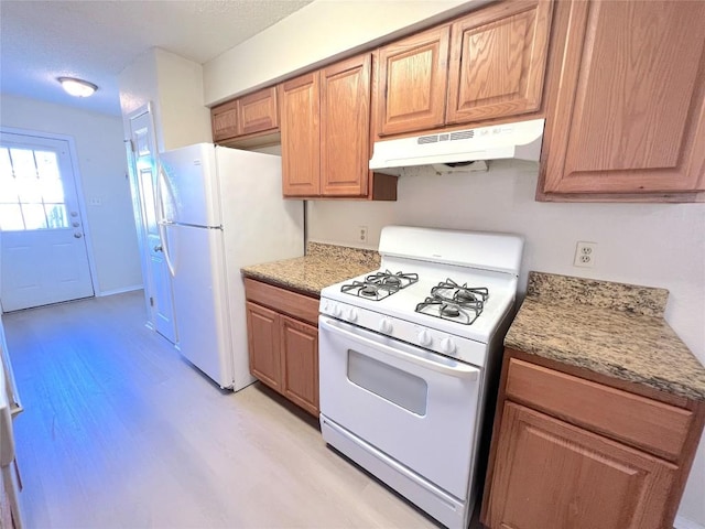 kitchen with light stone counters, white appliances, and light hardwood / wood-style floors