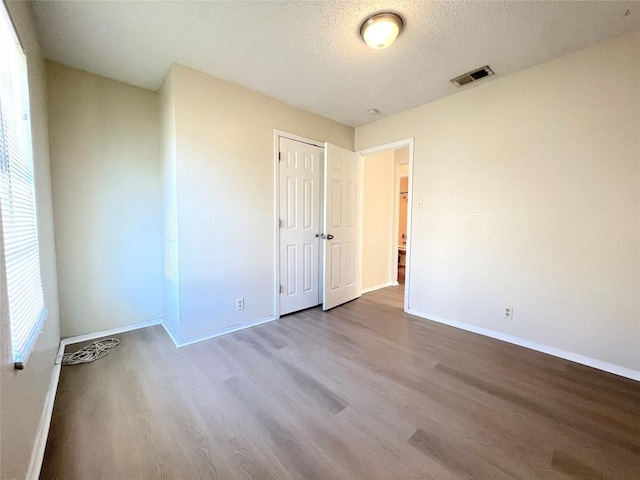 spare room with light hardwood / wood-style floors and a textured ceiling