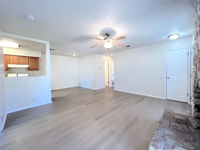 unfurnished room featuring ceiling fan, a textured ceiling, and light wood-type flooring