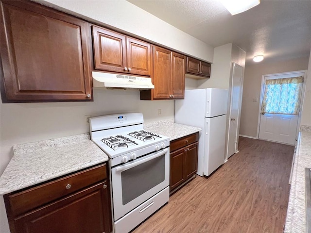 kitchen with white appliances and light hardwood / wood-style flooring