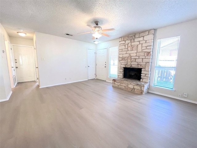 unfurnished living room featuring hardwood / wood-style floors, a textured ceiling, a fireplace, and ceiling fan