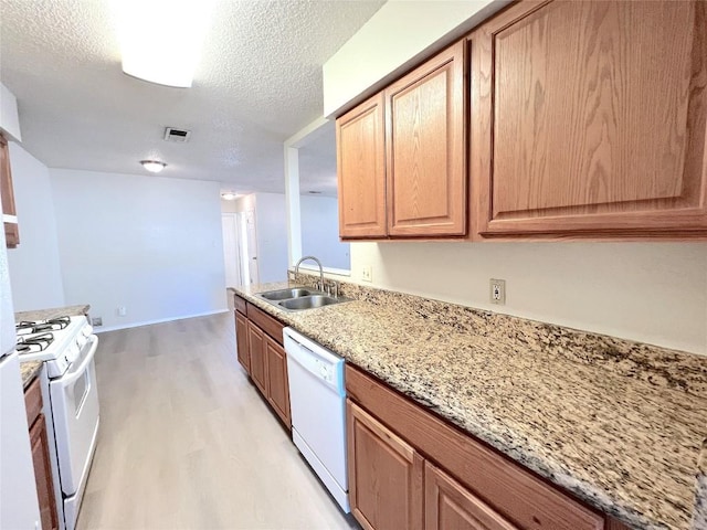 kitchen with sink, light stone counters, a textured ceiling, light wood-type flooring, and white appliances