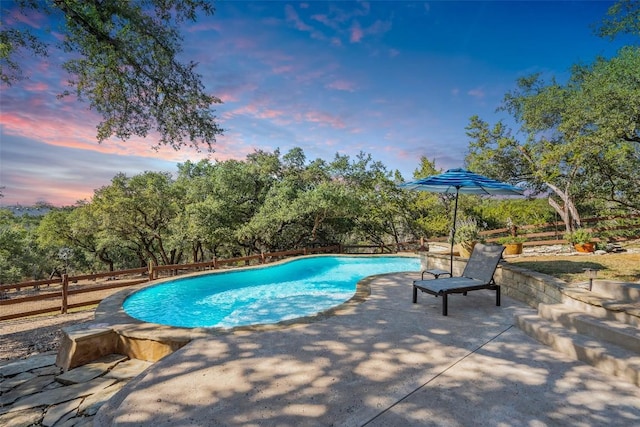 pool at dusk featuring a patio