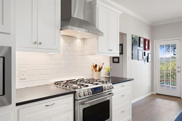 kitchen with crown molding, stainless steel gas range, white cabinetry, tasteful backsplash, and wall chimney exhaust hood