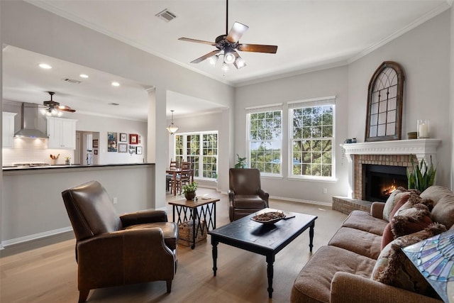 living room with ornamental molding, a brick fireplace, and ceiling fan