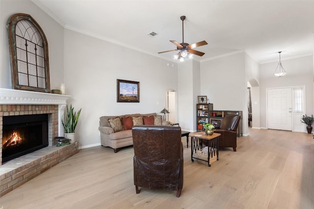 living room with a fireplace, ornamental molding, and light hardwood / wood-style floors