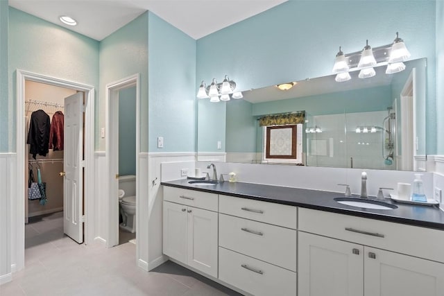 bathroom with a shower with door, vanity, tile patterned floors, and toilet