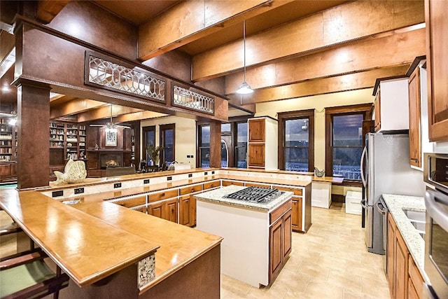 kitchen with a spacious island, stainless steel gas cooktop, hanging light fixtures, a kitchen breakfast bar, and kitchen peninsula