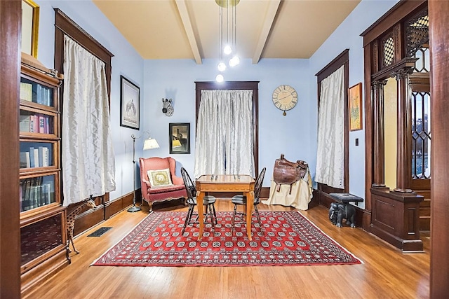 living area with hardwood / wood-style floors, decorative columns, and beamed ceiling