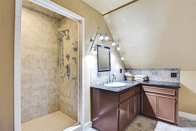 bathroom featuring vanity, lofted ceiling, and tiled shower