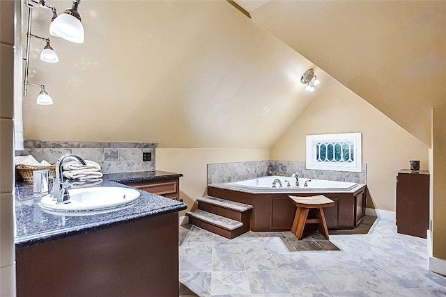 bathroom featuring vanity, a bathing tub, and vaulted ceiling